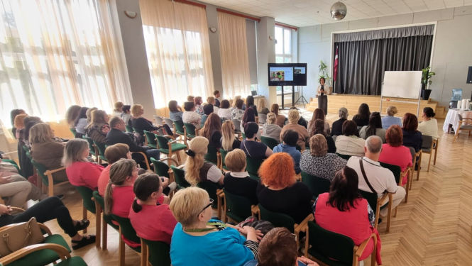Zāle pilna ar dalībniekiem, kuri klausās runātājā