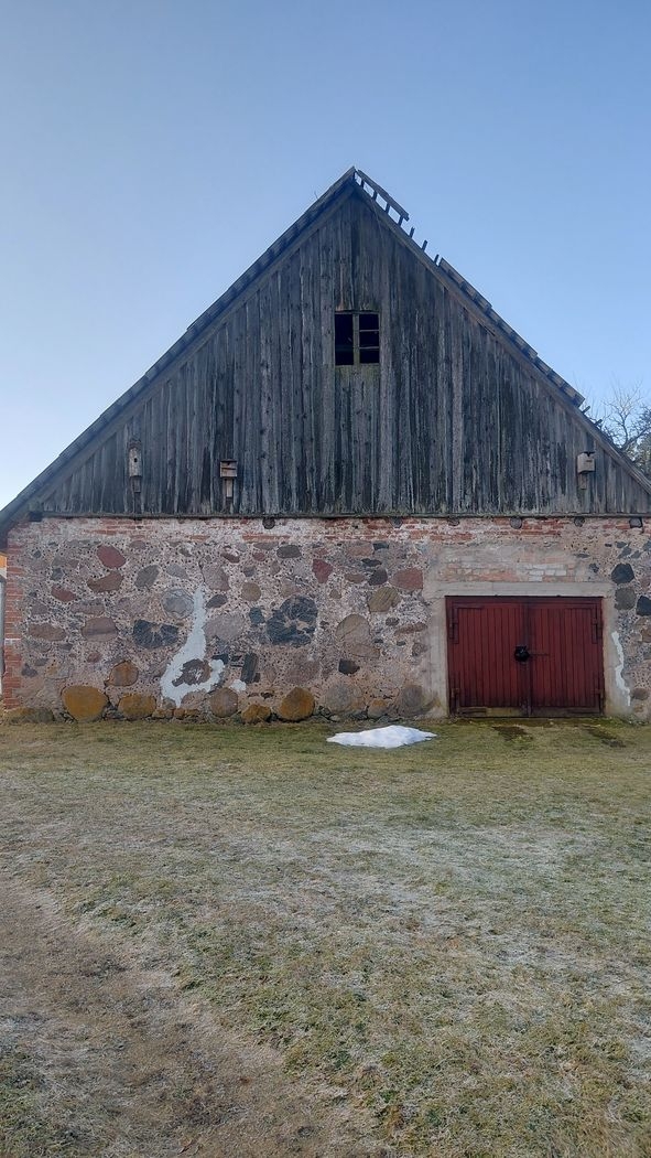 Akmens māja ar redzamu jumta daļas bojājumu