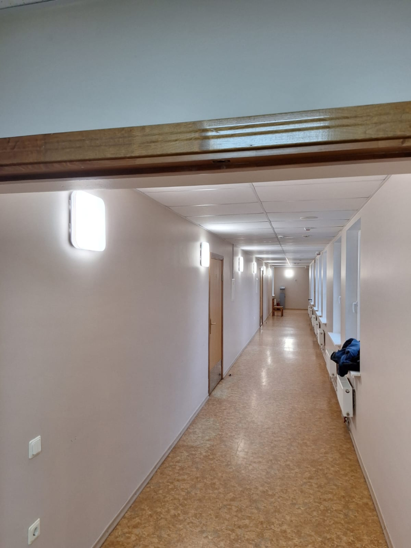 Attēlā gaitenis, kurā pie sienas pievienoti jaunie gaismekļi