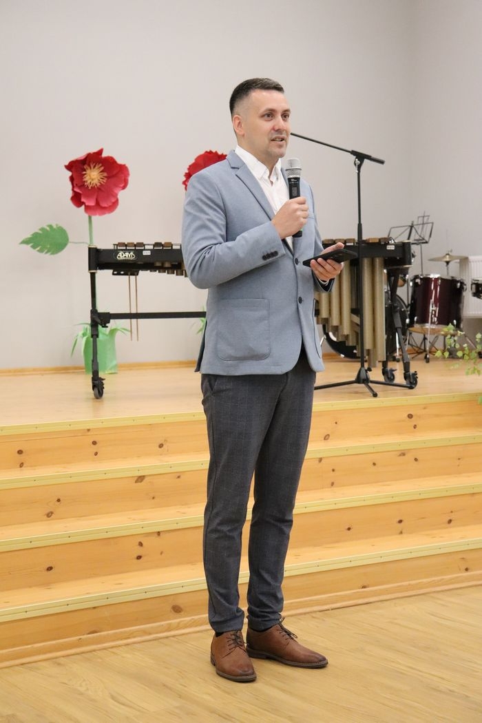 Zāles priekšā iestādes direktors ar mikrofonu