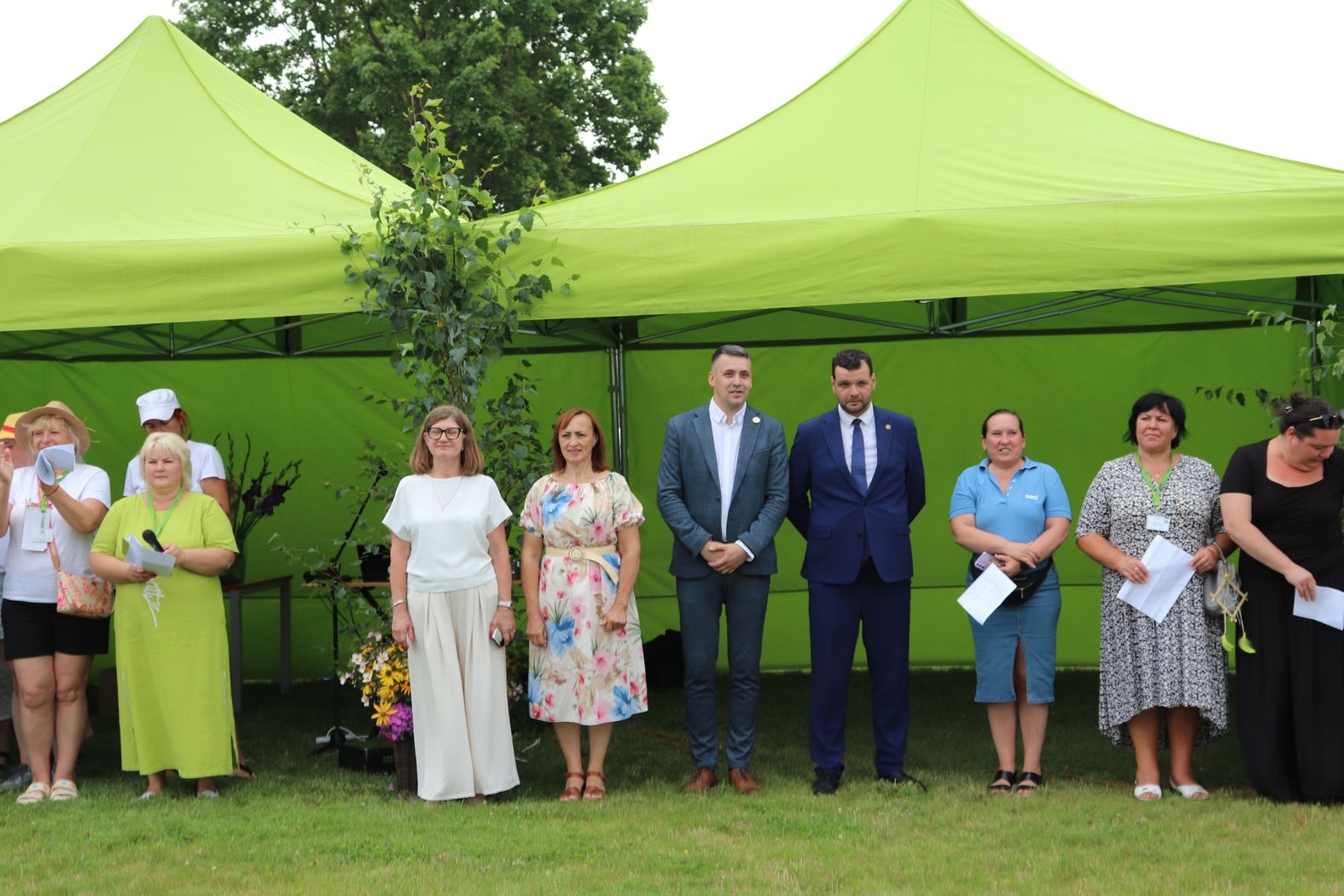 Atklāšanas pasākums, pie zaļajām teltīm rindā stāv organizatori un vadītāji un viesi