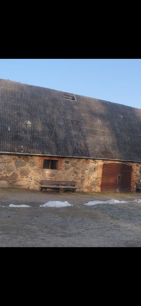 Akmens māja ar redzamu jumta daļas bojājumu