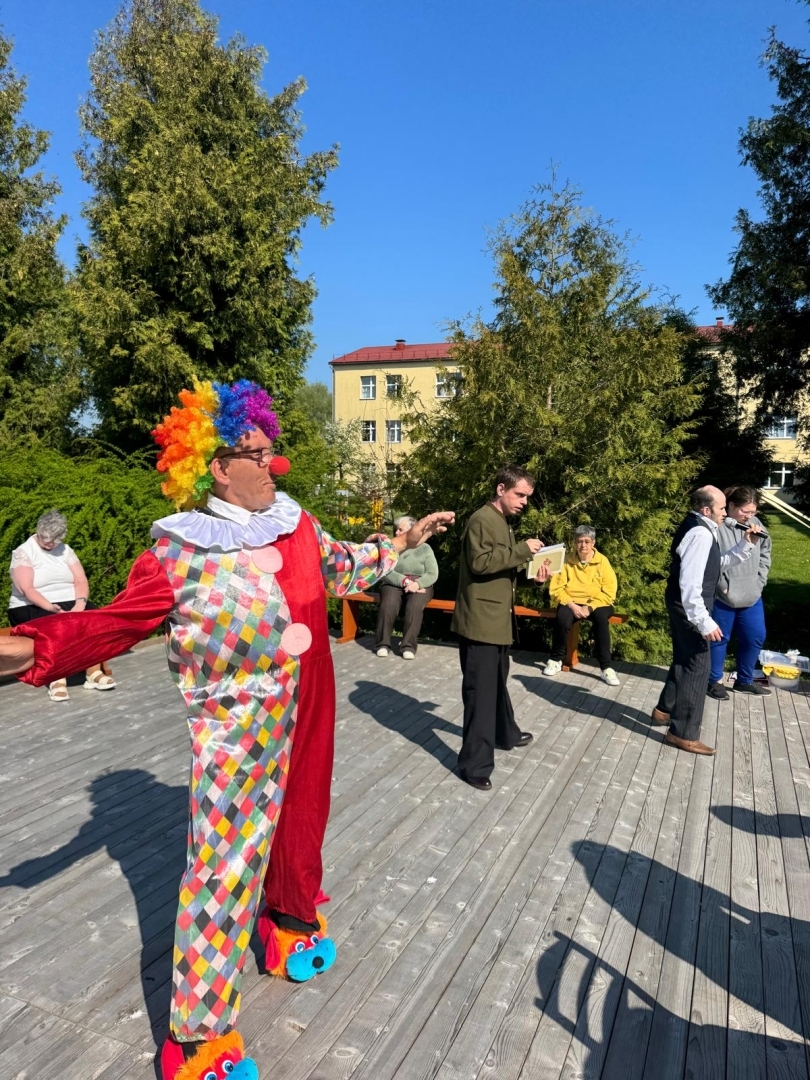 Notiek izrāde. Priekšplānā cilvēks tērpies klauna kostīmā