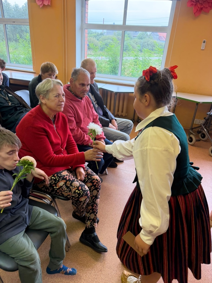 Meitene tautastērpā pasniedz ziedu kundzei
