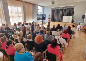 Zāle pilna ar dalībniekiem, kuri klausās runātājā