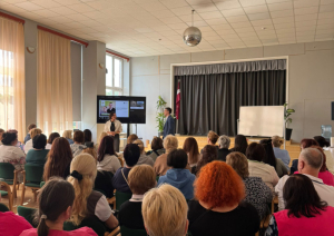 Zāle pilna ar dalībniekiem, kuri klausās runātājā