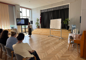 Zāle pilna ar dalībniekiem, kuri klausās runātājā