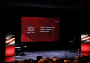 Labklājības ministrijas nozares labāko darbinieku godināšanas pasākuma skatuve. Lielais ekrāns ar ģerboni un uzrakstu "Labklājības nozares labāko darbinieku godināšana"