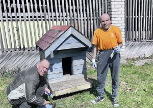 Divi cilvēki krāso suņu būdu