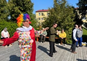 Notiek izrāde. Priekšplānā cilvēks tērpies klauna kostīmā