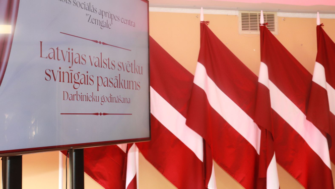 Pasākuma noformējums, ekrāns un fonā Latvijas karogi