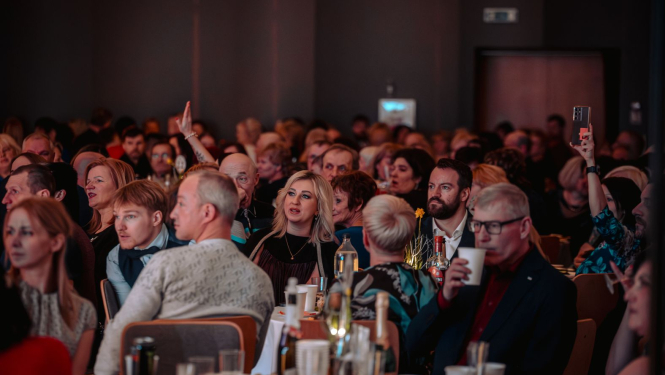 Pasākuma dalībnieki sēž pie galdiem