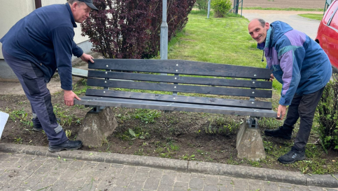 Filiāles "Rūja" darbinieks un iedzīvotājs fotogrāfijā pie atjaunotā sola