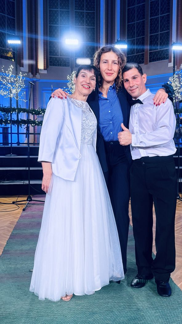 Pasākuma dalībnieki, dejotāji baltajos tērpos kopā ar pulciņa audzinātāju