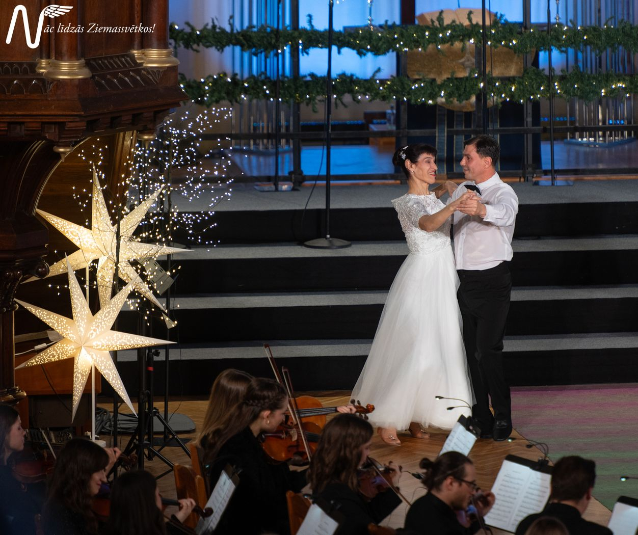 Pasākuma dalībnieki, dejotāji baltajos tērpos dejo baznīcā