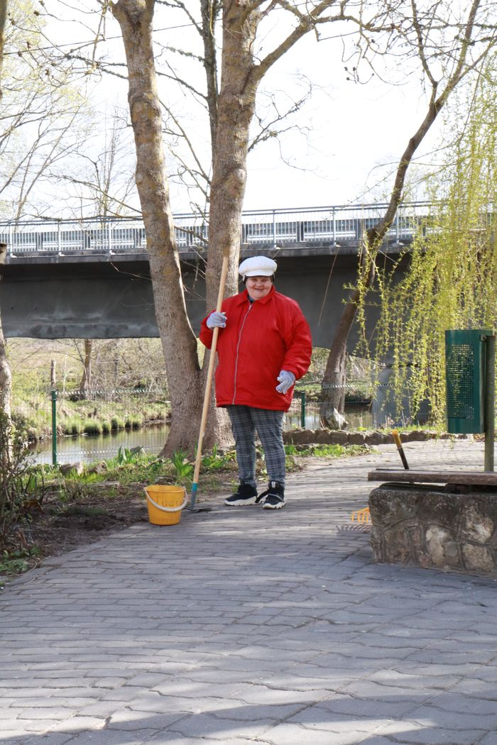 Sieviete veic teritorijas uzkopšanas darbus