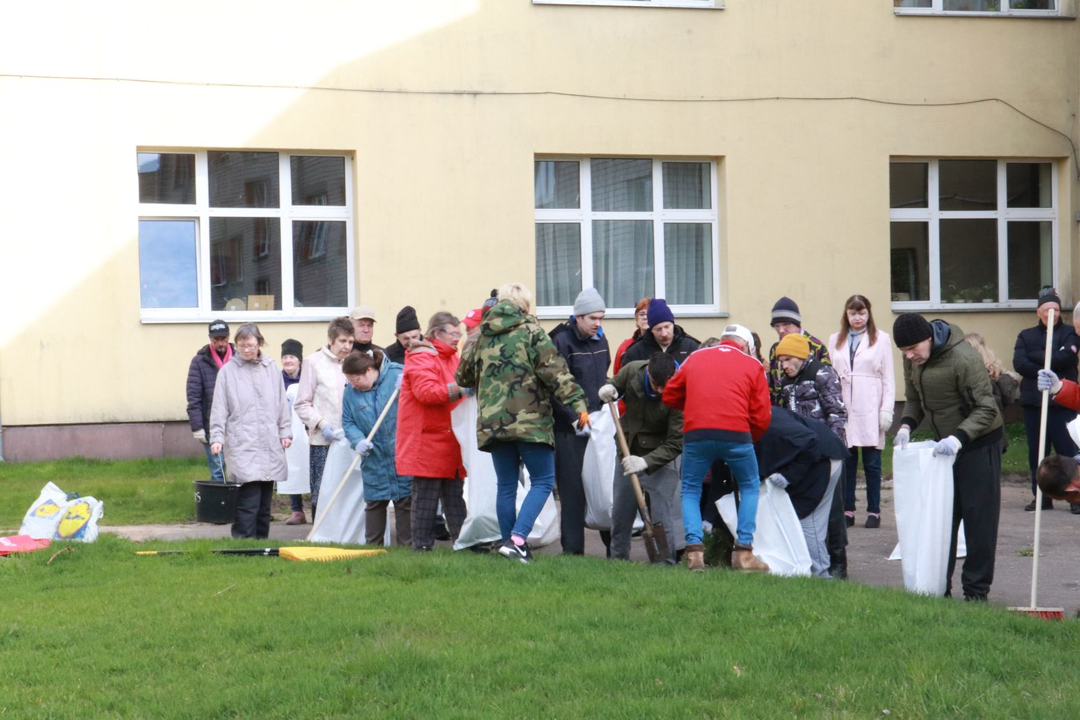 Cilvēki veic teritorijas uzkopšanas darbus