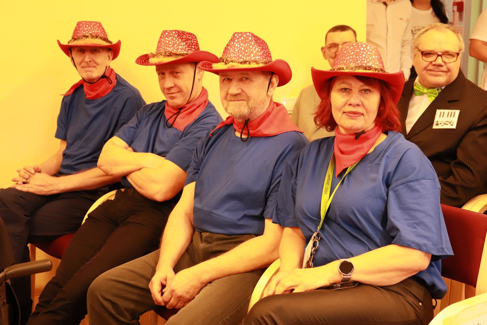 Pasākuma dalībnieku komanda sarkanajās kovboja cepurēs, smaidīgi