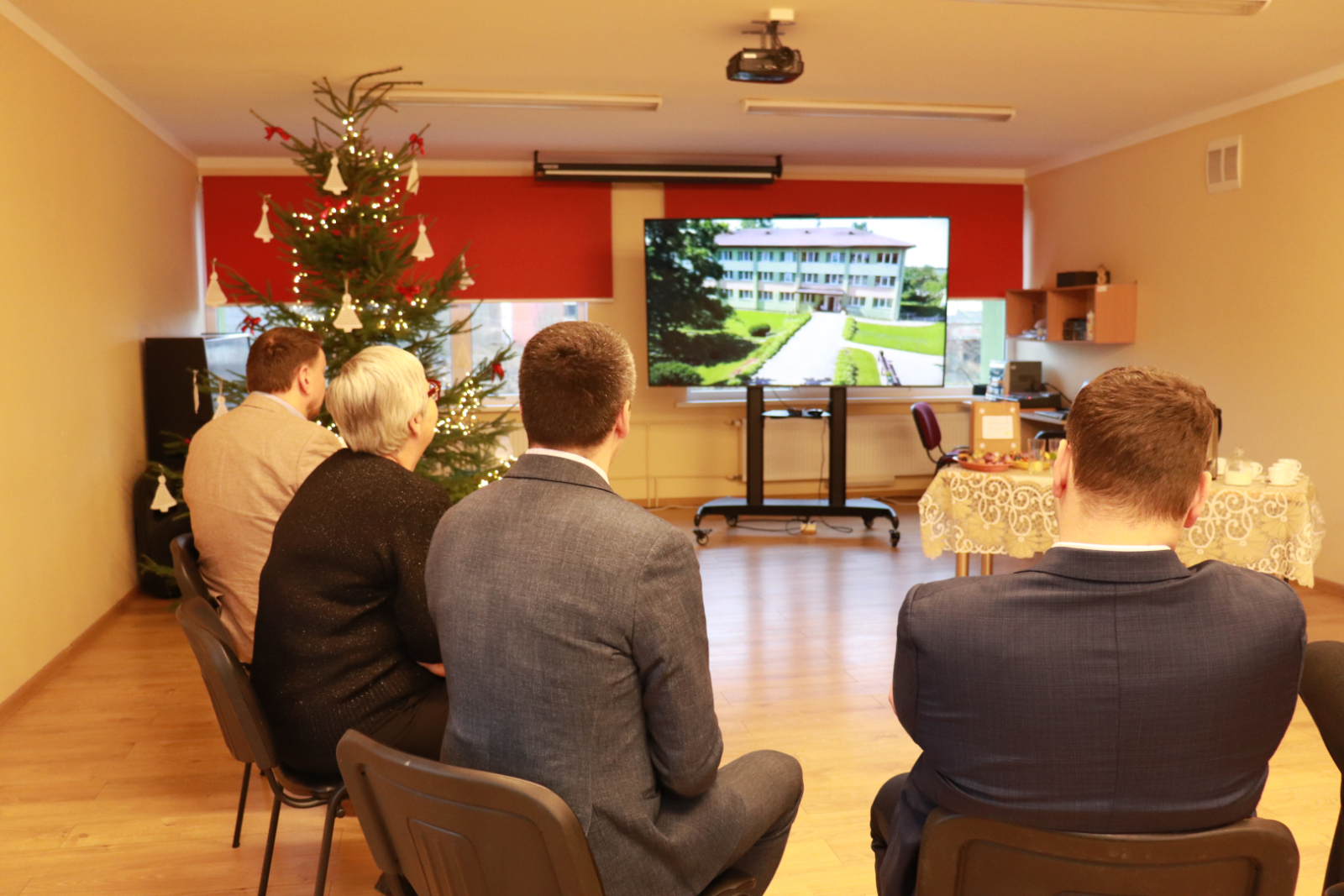 Filiāles viesi sarunājas, iestādes direktors un filiāles vadītāja skatās digitālu prezentāciju