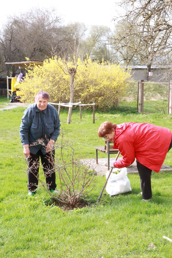 Cilvēki veic teritorijas uzkopšanas darbus