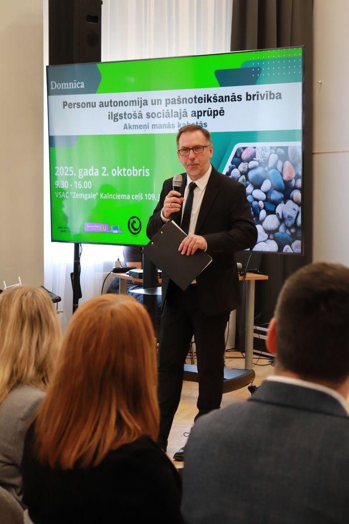 Domnīcas moderators runā mikrofonā