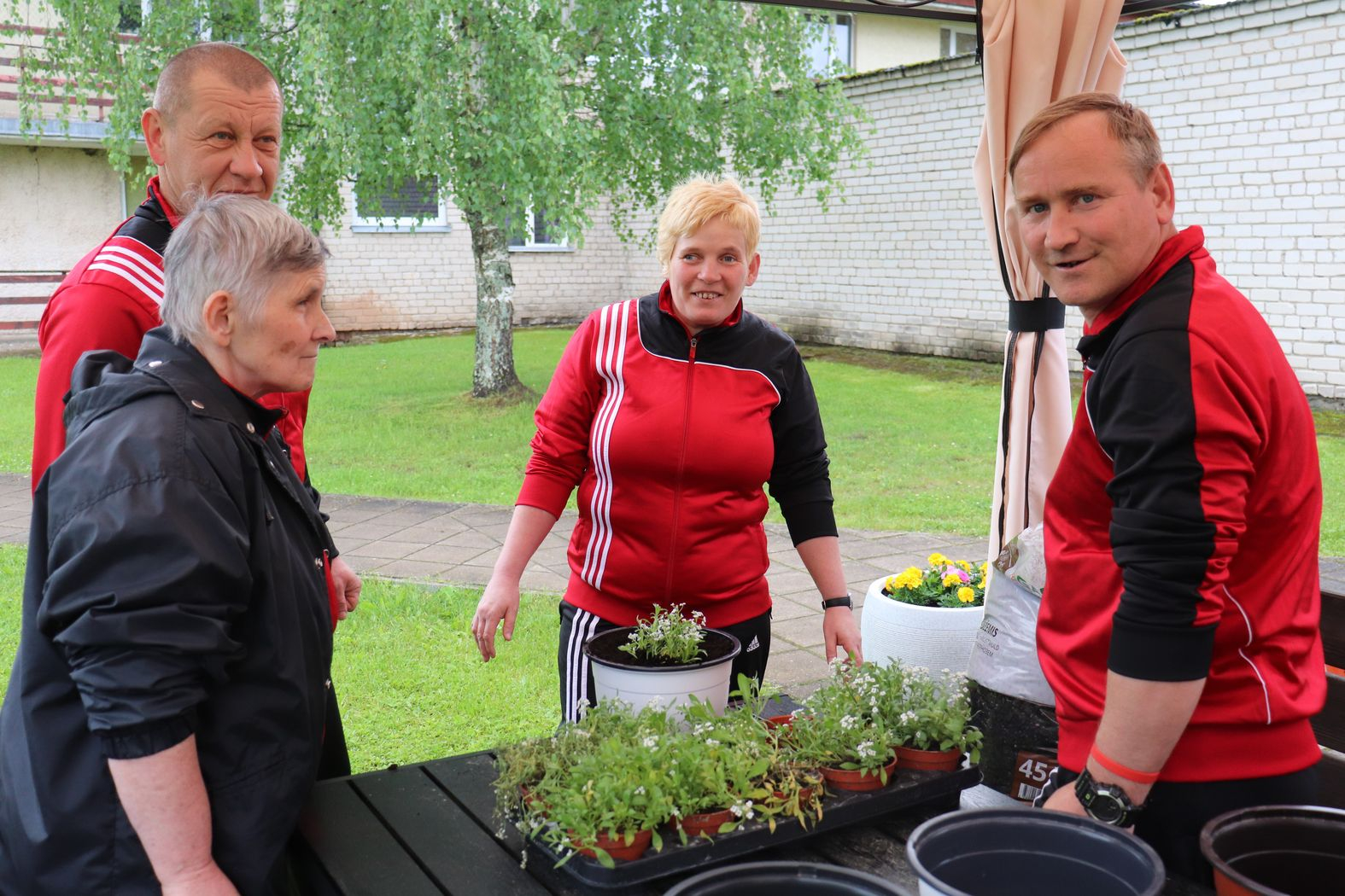 Dalībnieku komanda stāda puķes