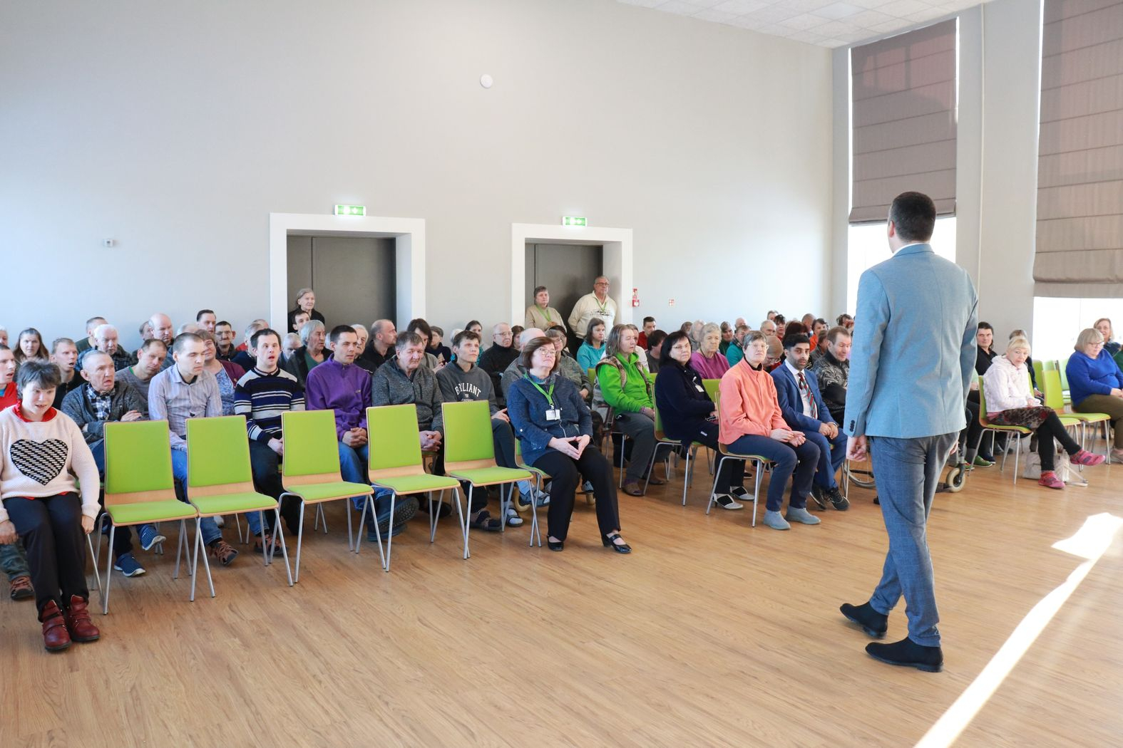 Zālē sēž iestādes iedzīvotāji, priekšā iestādes direktors vada kopsapulci