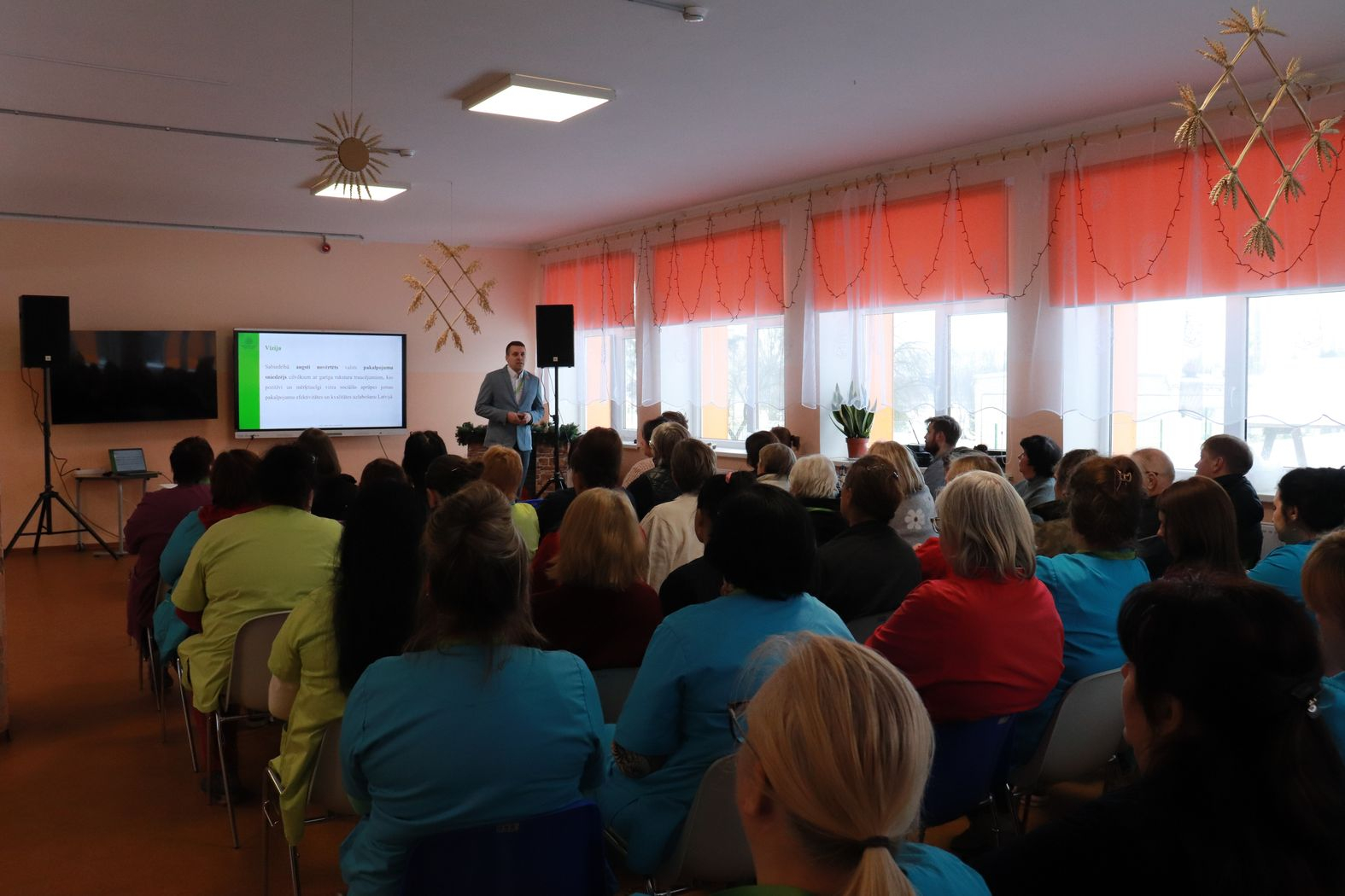 Zālē sēž darbinieki, priekšā iestādes direktors vada kopsapulci