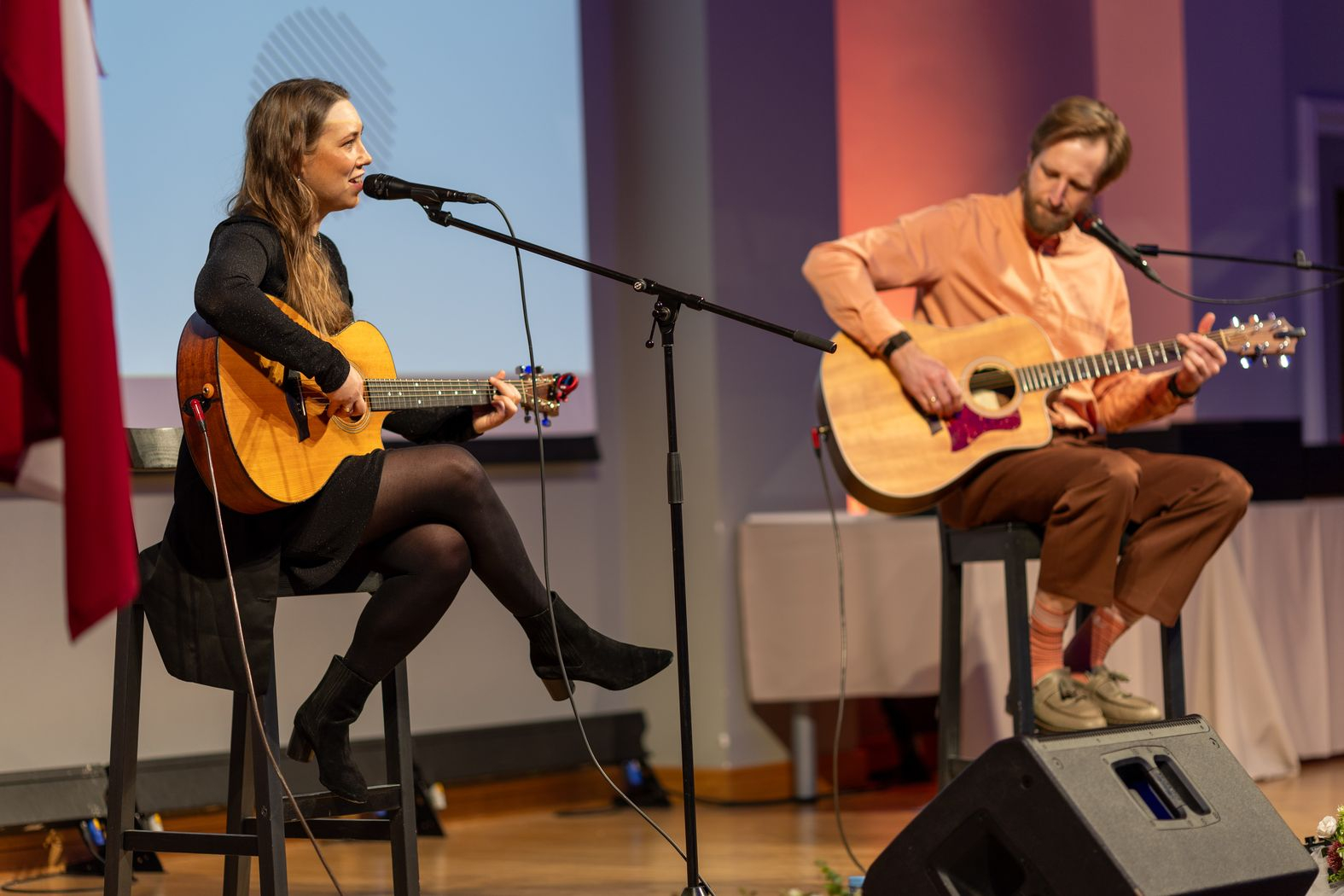 Uz skatuves izpildītāji ar ģitārām dzied dziesmas