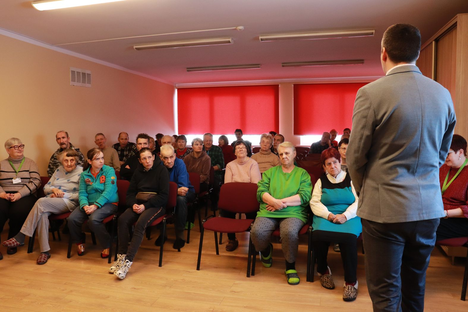 Zālē sēžiedzīvotāji, priekšā iestādes direktors vada kopsapulci