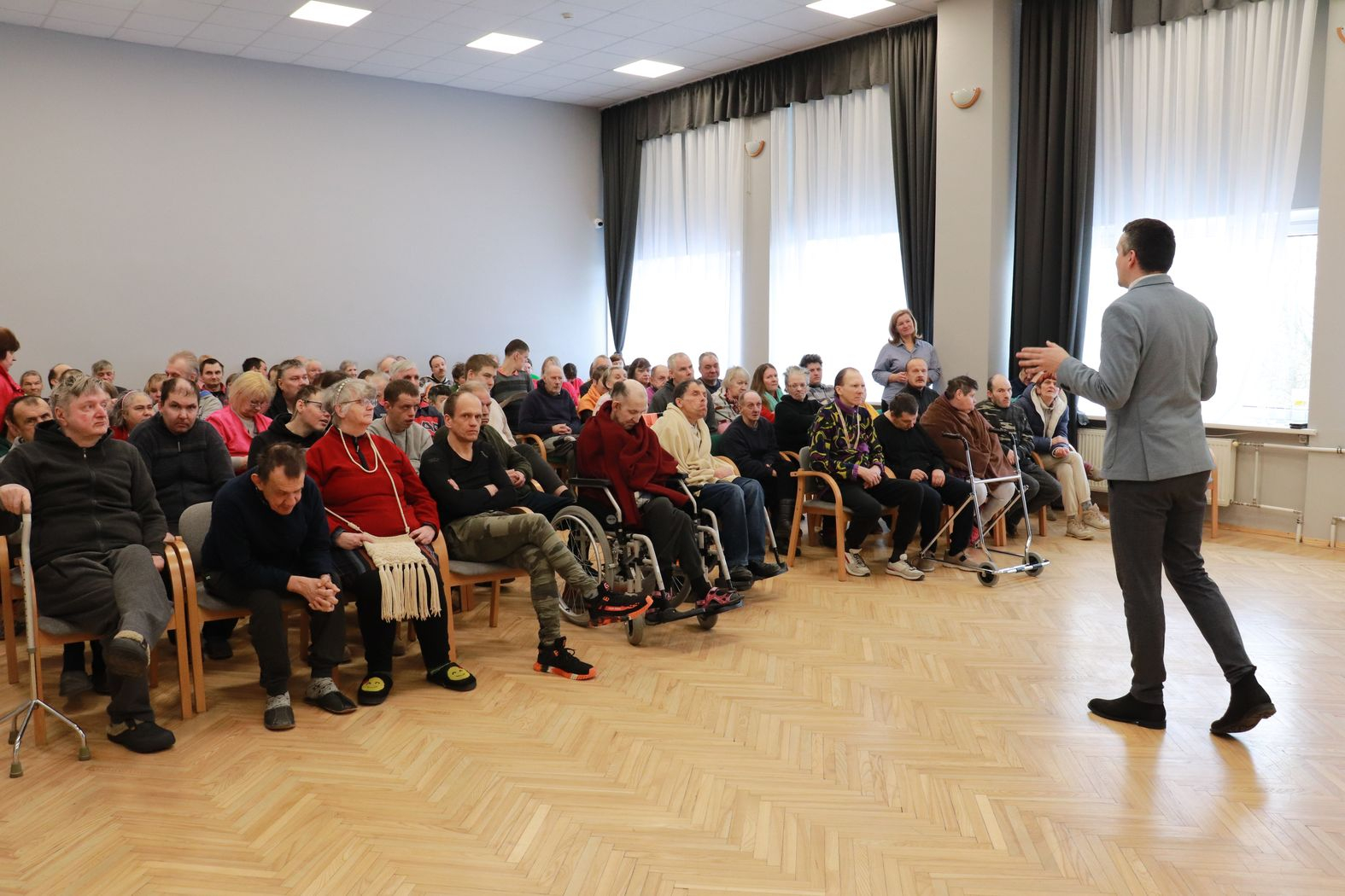 Zālē sēž iedzīvotāji, priekšā iestādes direktors vada kopsapulci