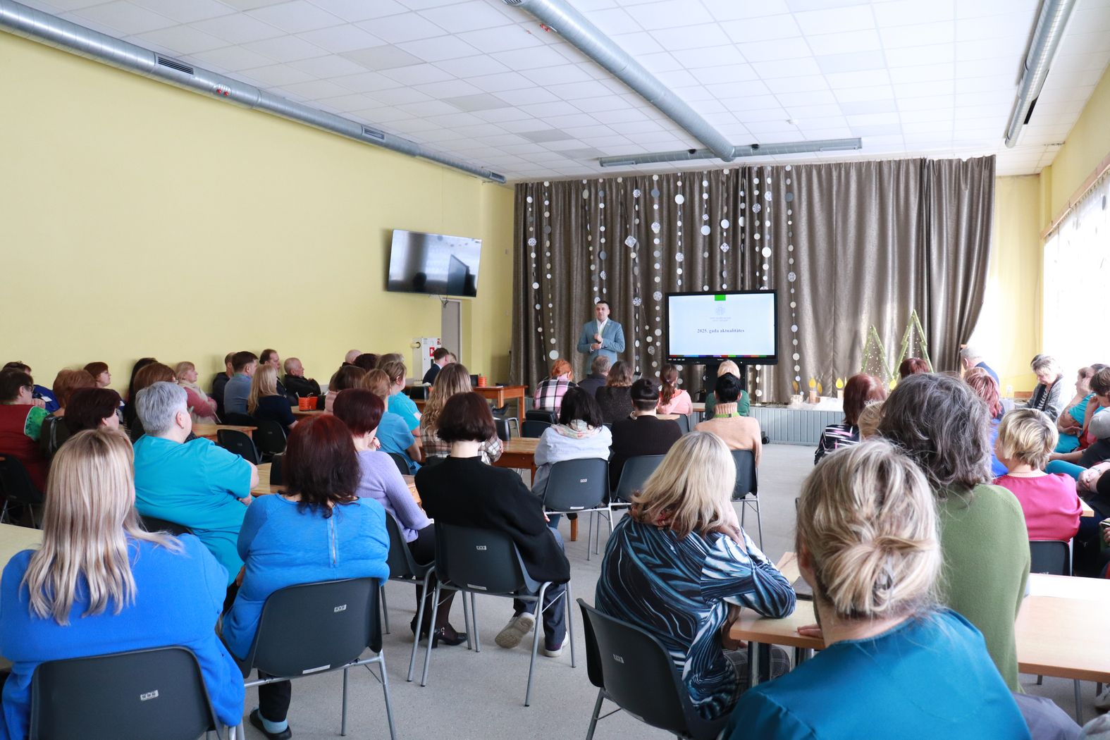 Zālē sēž darbinieki, priekšā iestādes direktors vada kopsapulci