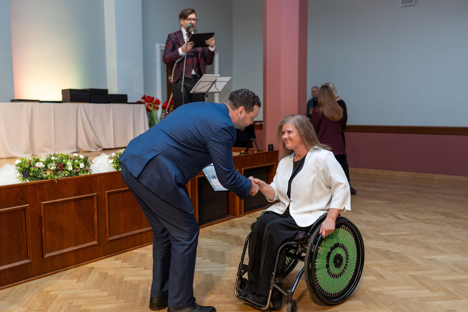 Apbalvojuma saņēmējs ar ziediem, pateicību kopbildē ar labklājības ministru 