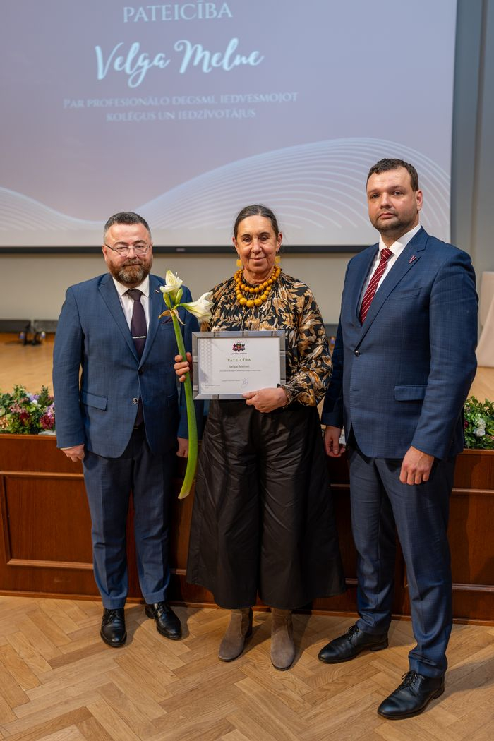 Apbalvojuma saņēmējs ar ziediem, pateicību kopbildē ar labklājības ministru un valsts sekretāru