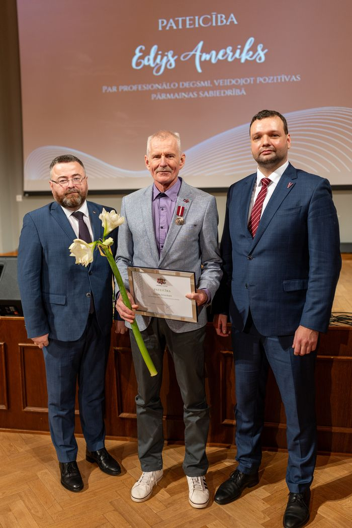 Apbalvojuma saņēmējs ar ziediem, pateicību kopbildē ar labklājības ministru un valsts sekretāru