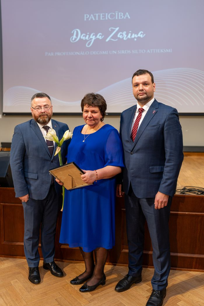 Apbalvojuma saņēmējs ar ziediem, pateicību kopbildē ar labklājības ministru un valsts sekretāru