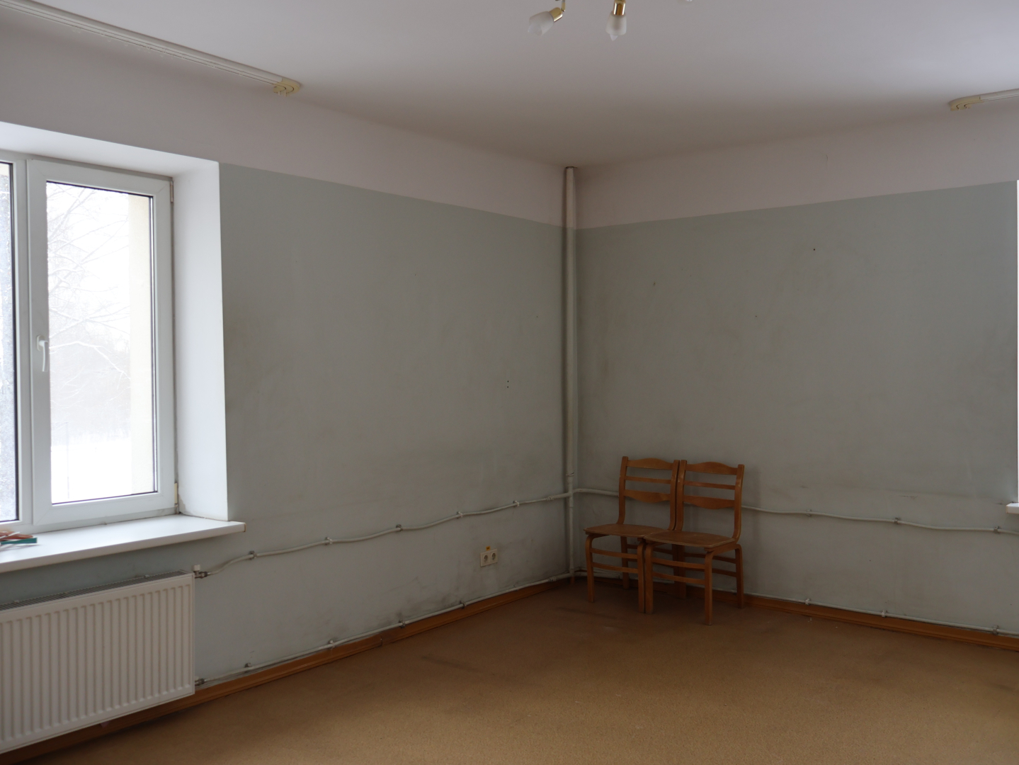 Attēlā telpa pirms remontdarbu uzsākšanas. Blāvi pelēka sienas krāsa, nobružātas sienas.
