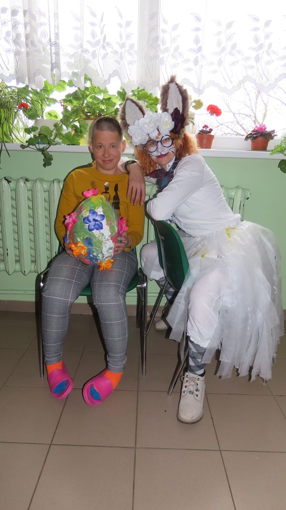 Divi cilvēki, vienam rokās liela krāsaina ola, otrs pārģērbies par zaķi