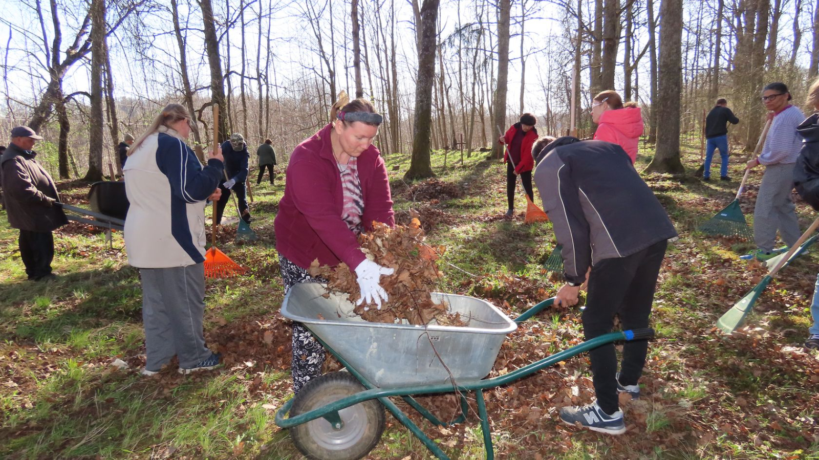 Cilvēki veic teritorijas uzkopšanas darbus