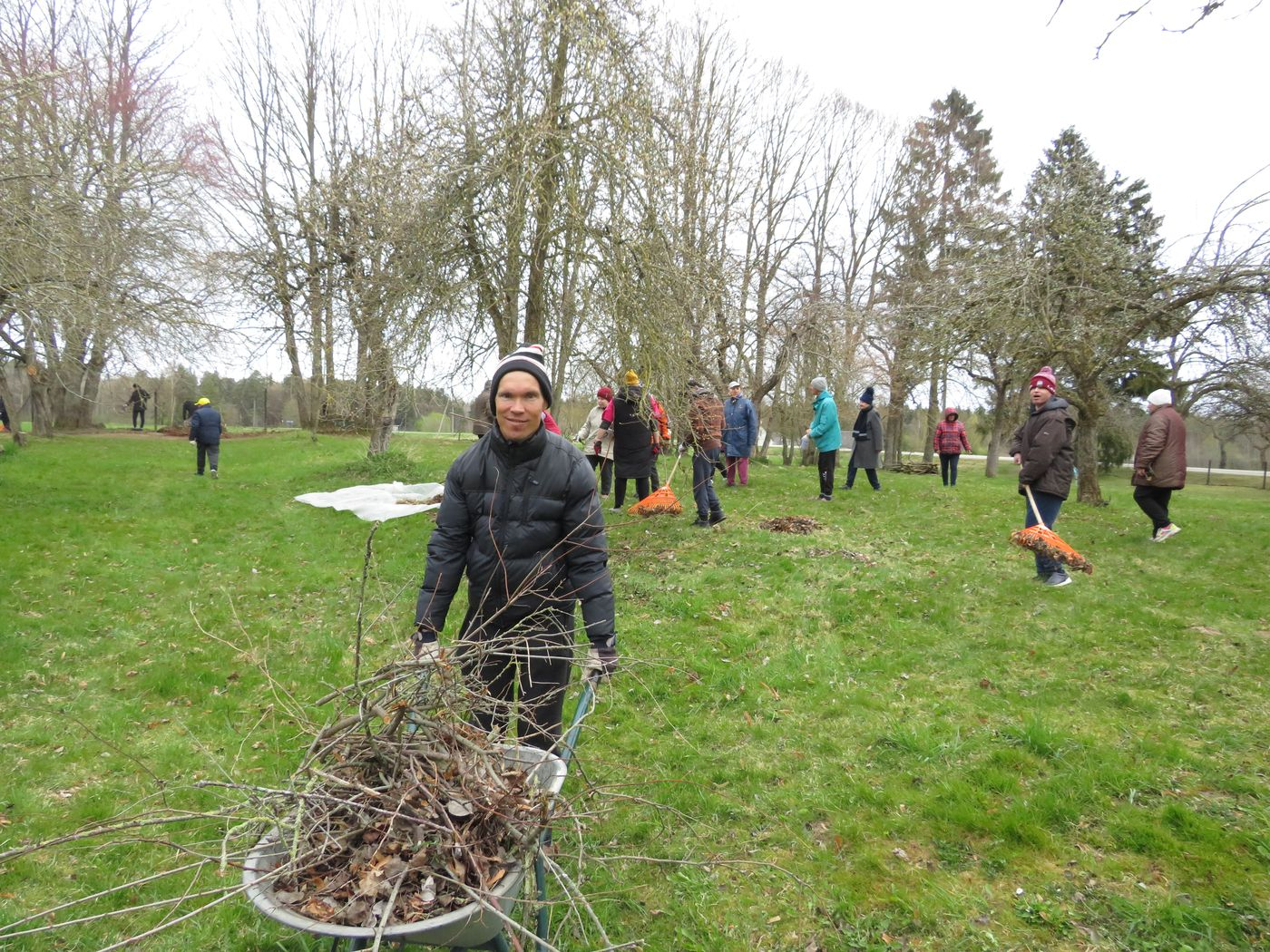 Cilvēki veic teritorijas uzkopšanas darbus