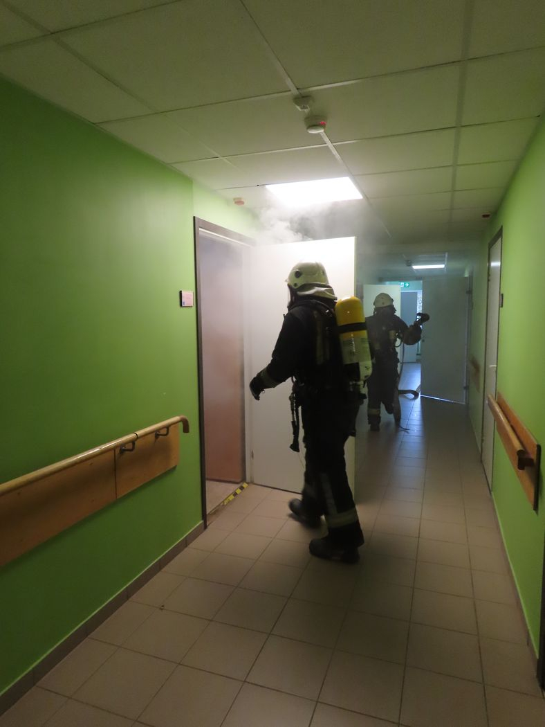 Ugunsdzēsējs gatavojas ieiet telpā, no kuras nāk dūmi