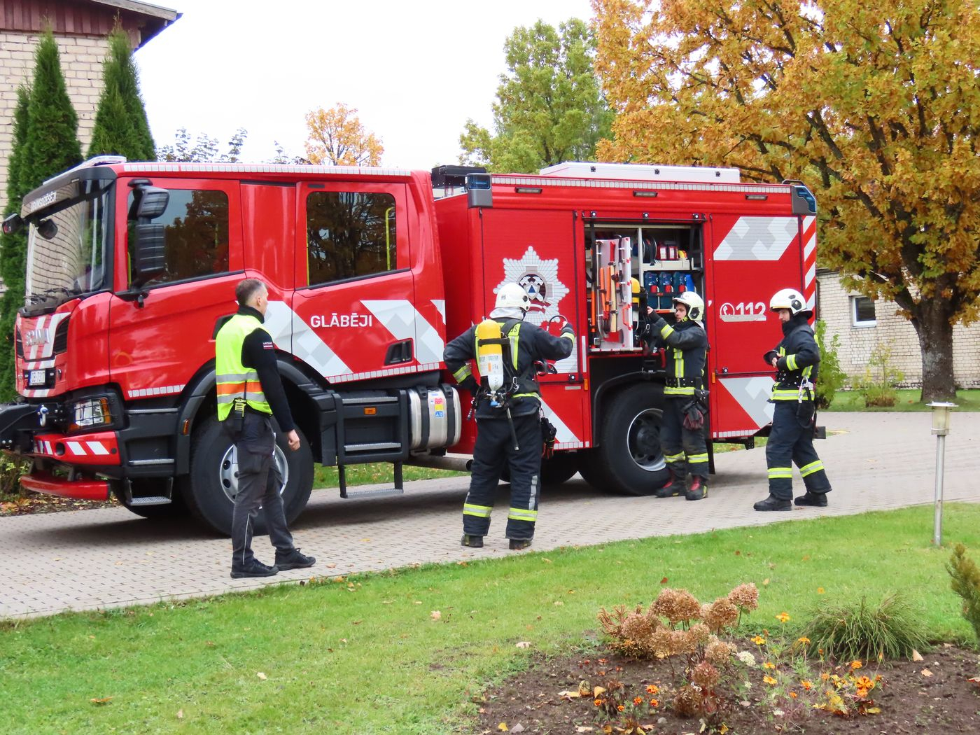 četri ugunsdzēsēji pie ugunsdzēsēju automašīnas