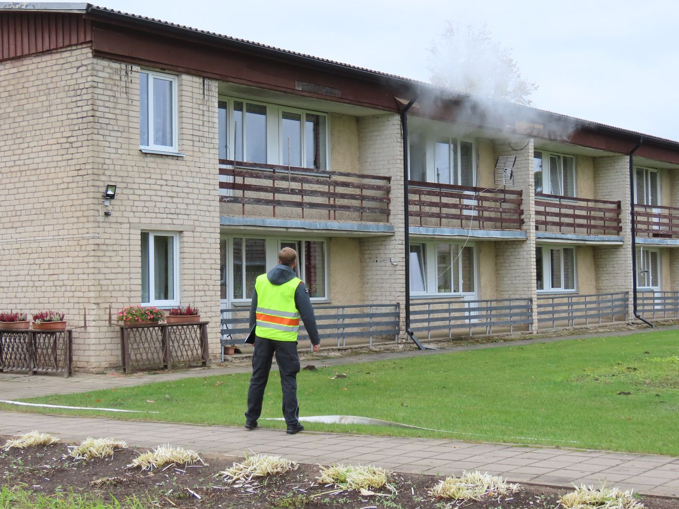 Attēlā ēka, no kuras pa logu nāk dūmi