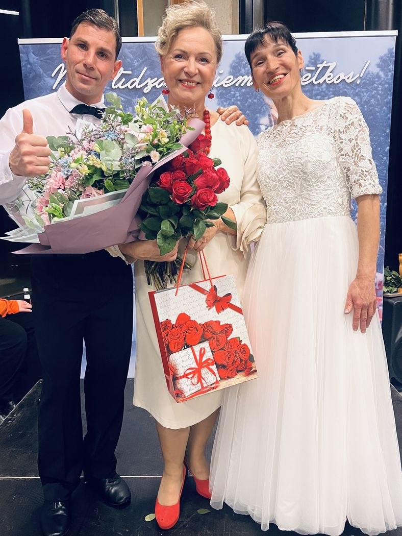 Pasākuma dalībnieki, dejotāji baltajos tērpos ar fonda vadītāju Sarmu