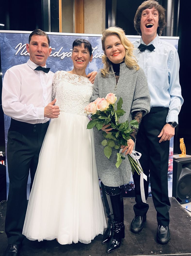 Pasākuma dalībnieki, dejotāji baltajos tērpos ar dziedātāju Anniju Putniņu