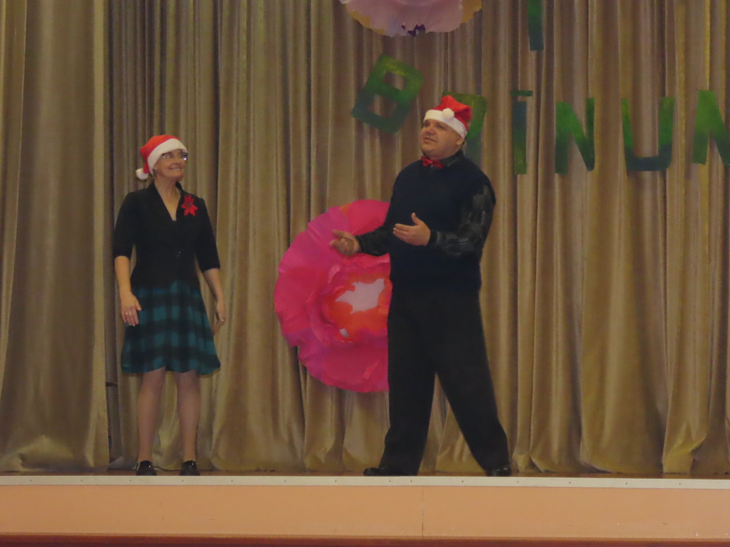 Divi dalībnieki uz skatuves rūķu cepurēs