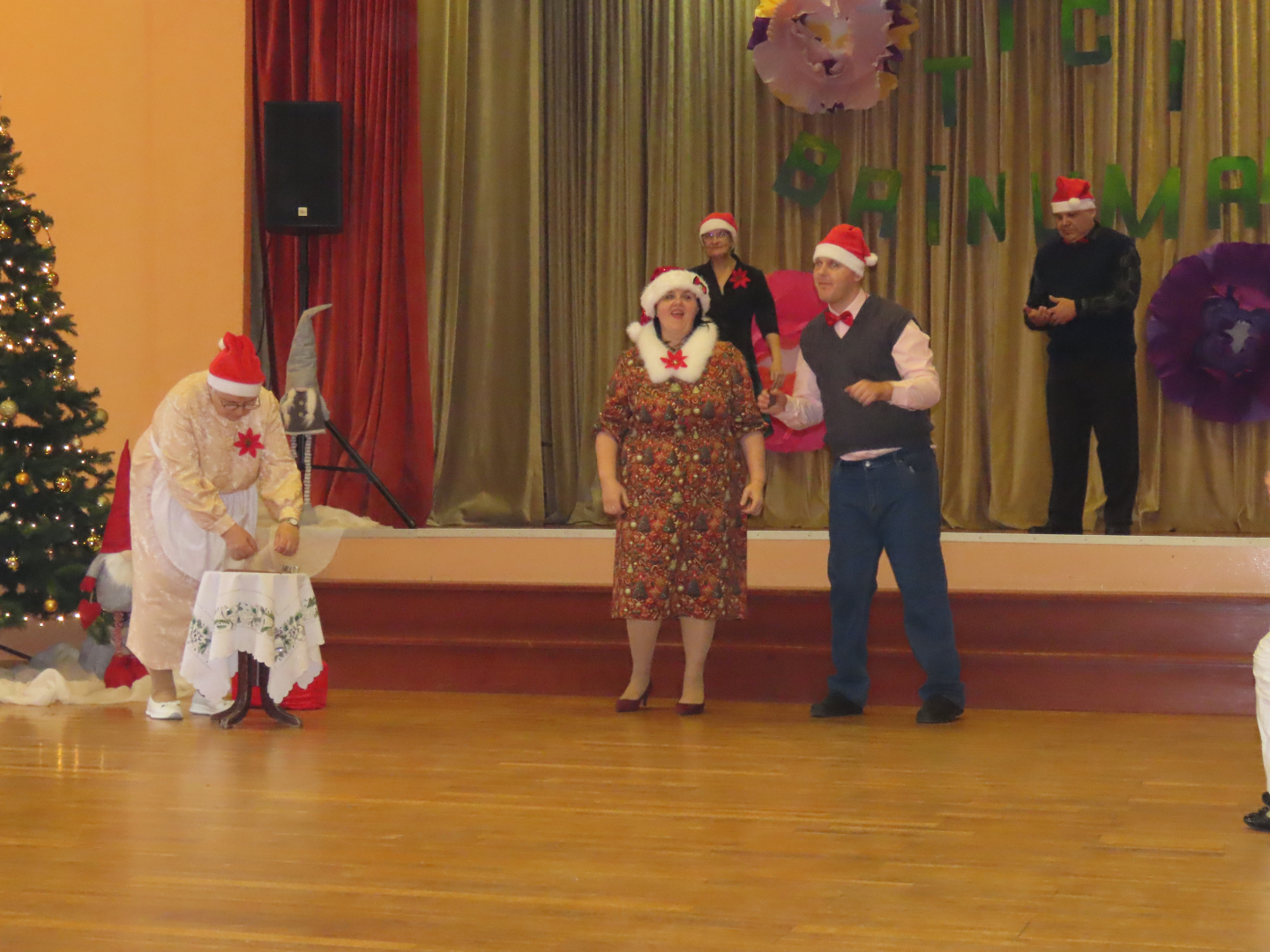 Dalībnieki uz skatuves rāda priekšnesumu, visiem galvā rūķu cepures