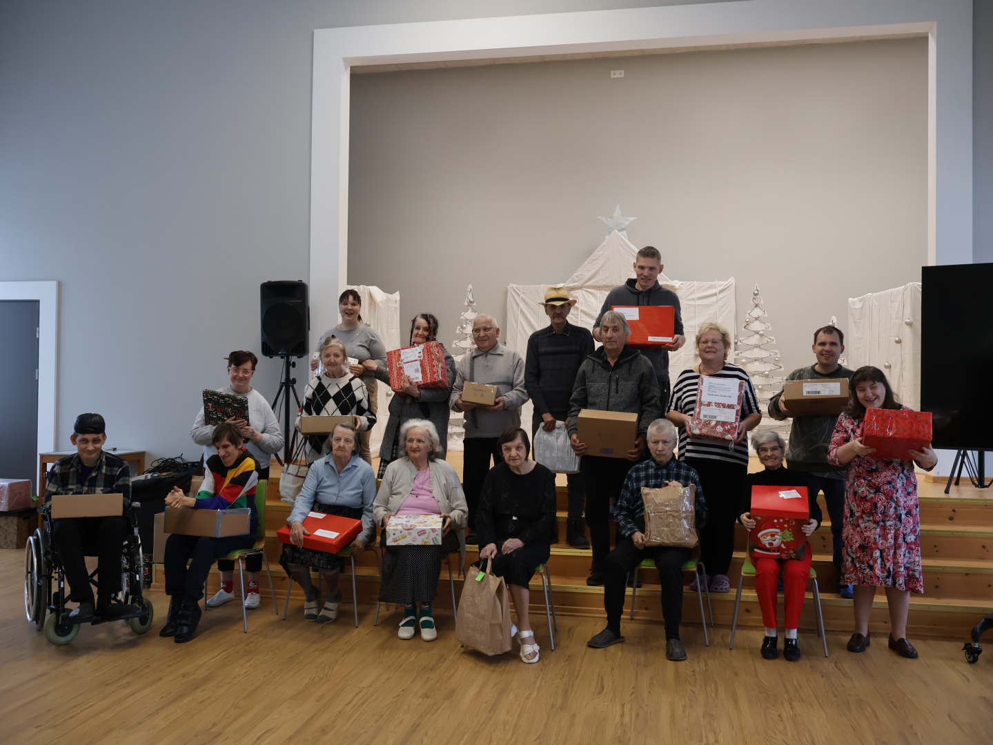 Smaidīgi iedzīvotāji zālē ar dāvanām rokās