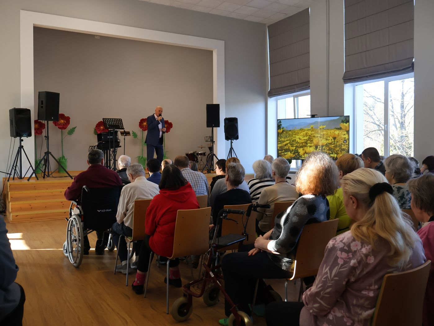 Skatītāji bauda koncertu. Uz skatuves dziedātājs pie mikrofona