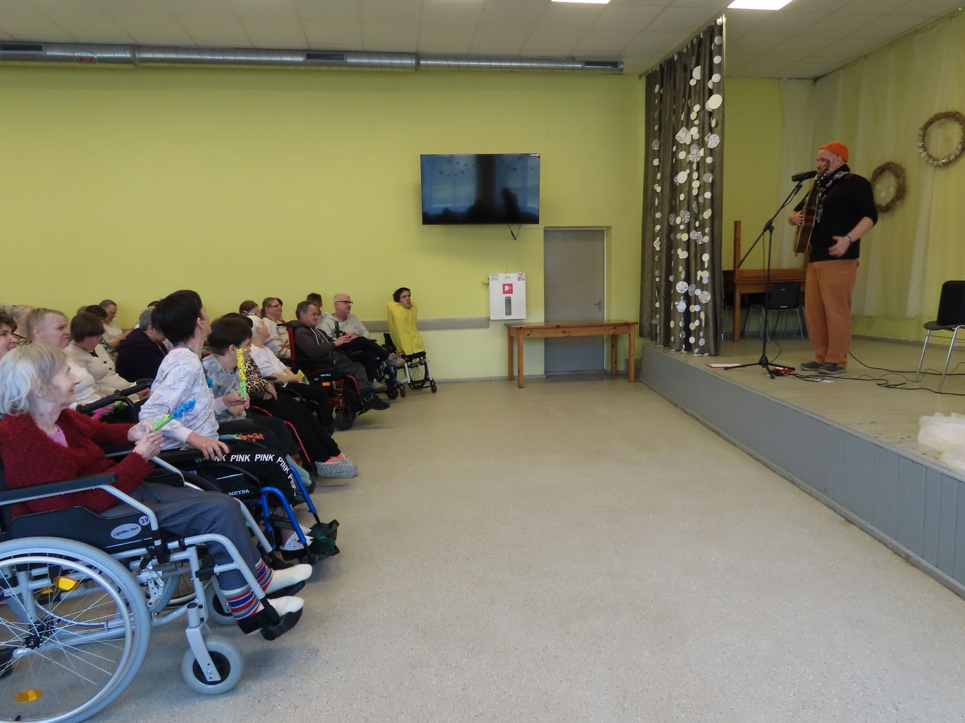 Skatītāji bauda oncertu. Uz skatuves dziesminieks pie mikrofona